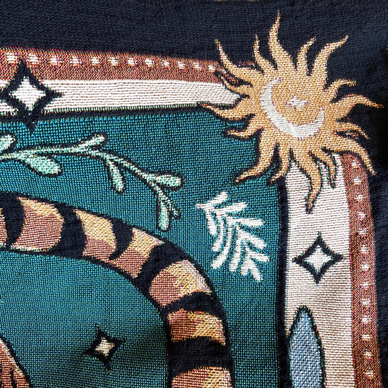 May include: A tapestry with a teal background featuring a tiger, a sun, and a stylized tree. The tiger is brown and black with orange stripes. The sun is yellow with a white face. The tree is white with green leaves.