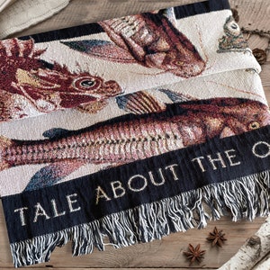 Unique Fathers Day Gift Idea. An ideal Fathers day gift for him this cotton blanket has beautiful vintage fish woven into an ivory black ground. The vintage fish are warm reds and deep purples. The ivory blankets black border can be personalized.