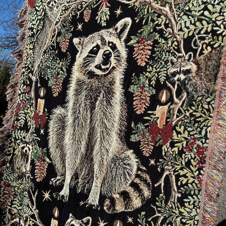 Raccoon decor for raccoon lovers. Black woven tapestry blanket with raccoons and festive red bows, candles and stars woven throughout. All cotton woven design. Not printed