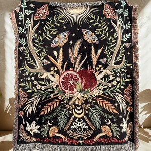 The story of Persephone and Hades woven into a cotton woven blanket with fringe. Hades symbolism is woven on the bottom of the blanket with Persephone's spring time return woven on the top. A central pomegranate separates the two worlds.
