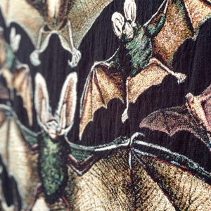 Warm earth toned bats on a black background. 100% cotton Halloween woven throw with fringe around the edges.