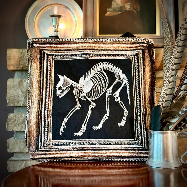 Cat skeleton tote bag. Victorian Gothic tote bag with vintage Halloween aesthetic. This woven tapestry tote bag has a white cat skeleton woven into a black background surrounded by an antique picture frame.