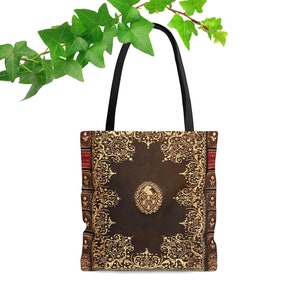 Op de afbeelding: Een bruine tote bag met een vintage boekomslagontwerp. De omslag heeft ingewikkelde gouden filigraan en een bruine lederen achtergrond.