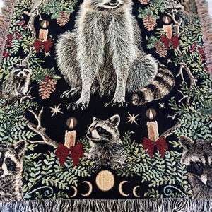 Looking for raccoon gifts? This Raccoon Christmas Blanket is perfect for raccoon lovers! The all cotton blanket has a detailed design of six raccoons, Christmas candles with red bows, winter botanicals, holly berries, pinecones and mistletoe woven in