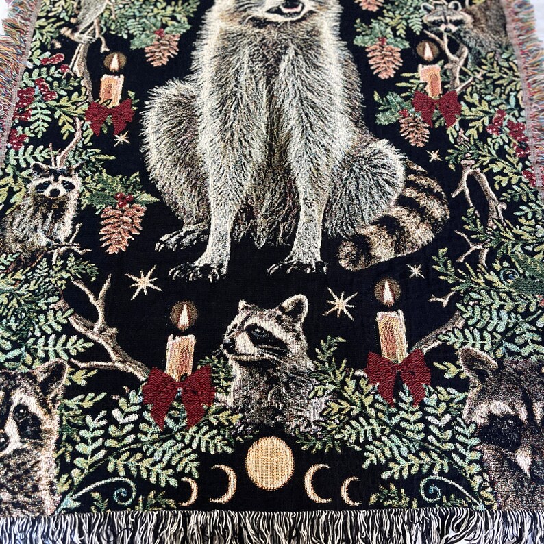 Looking for raccoon gifts? This Raccoon Christmas Blanket is perfect for raccoon lovers! The all cotton blanket has a detailed design of six raccoons, Christmas candles with red bows, winter botanicals, holly berries, pinecones and mistletoe woven in