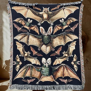 Vintage Bat Woven Blanket also available from Chelsea Green Studio. This woven tapestry blanket with fringe around the edges has a black background and several large vintage aesthetic bats woven into the black background. One Hundred Percent cotton.