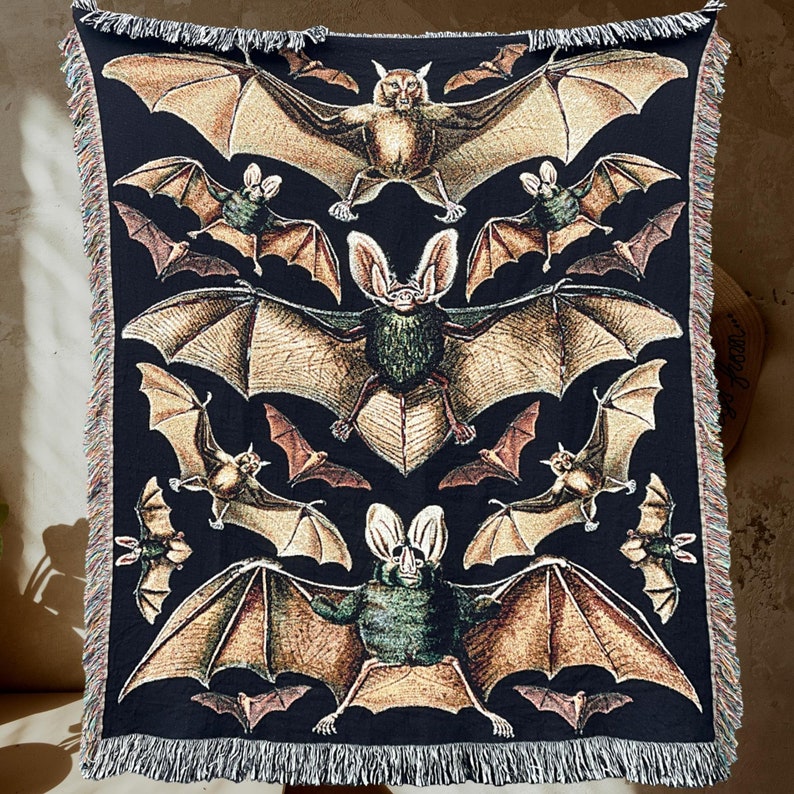 Vintage Bat Woven Blanket also available from Chelsea Green Studio. This woven tapestry blanket with fringe around the edges has a black background and several large vintage aesthetic bats woven into the black background. One Hundred Percent cotton.