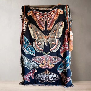 May include: A black woven tapestry throw blanket featuring a colorful butterfly design. The blanket has a fringe border and is decorated with various butterflies in shades of blue, green, red, orange, and yellow.