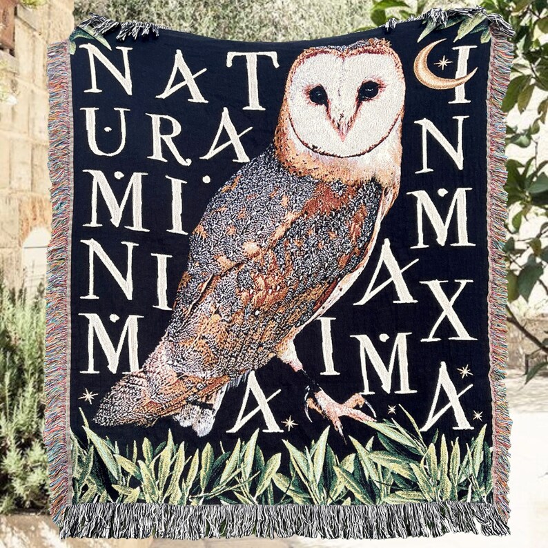 Dark academia decor woven blanket with owl and latin saying. Academia decor woven tapestry blanket with fringe around the all edges, black background, large detailed woven barn owl with the latin phrase Natura In Minima Maxima in large white letters