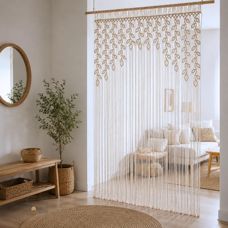 May include: A cream-colored macrame curtain hanging from a wooden rod, featuring a repeating leaf pattern at the top and long, vertical fringe strands that extend downward to create a decorative room divider with a knotted fiber design.