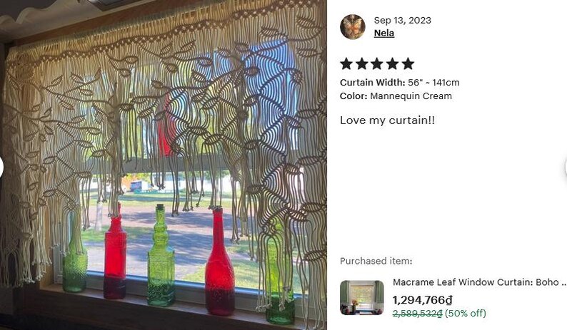 May include: A cream-colored macrame window curtain featuring a leaf pattern and fringe, measuring 56 inches in width. The curtain hangs in front of a window with several green and red glass bottles placed on the wooden windowsill below.