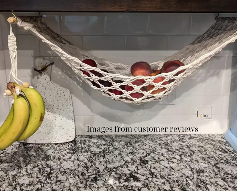 Puede incluir: Una hamaca de frutas de macram&eacute; hecha a mano llena de melocotones maduros, suspendida de una clavija de madera. Un racimo de pl&aacute;tanos cuelga de un cord&oacute;n decorativo de macram&eacute;. La encimera de la cocina es de granito.