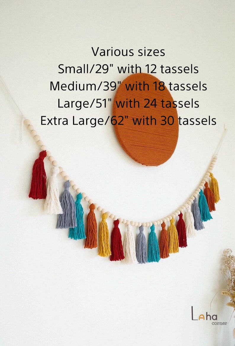 May include: A wooden bead garland with colorful tassels in red, white, gray, teal, orange, and yellow. The garland is 62 inches long and has 30 tassels. Various sizes are available: Small (29 inches, 12 tassels), Medium (39 inches, 18 tassels), Large (51 inches, 24 tassels).
