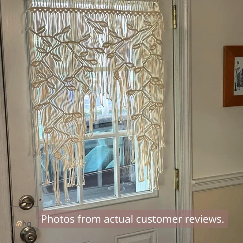 May include: An off-white macrame curtain featuring a repeating leaf pattern created with intricate knotted cord work. The piece hangs from a horizontal rod and ends in long, loose fringe strands that drape over the glass pane of a white door.