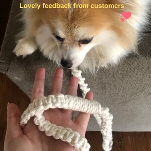Puede incluir: Una correa de macram&eacute; de color crema con textura anudada sostenida en una mano, con un peque&ntilde;o perro esponjoso mirando hacia la correa. El texto "Lovely feedback from customers" est&aacute; impreso en amarillo en la parte superior con un icono de coraz&oacute;n rosa.