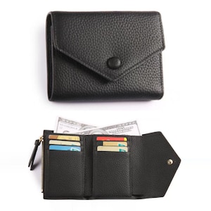 May include: Black leather wallet with a snap closure and a zippered compartment. The wallet is shown closed and open, revealing card slots and a bill compartment. The wallet is made of textured leather.