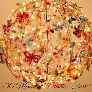 May include: A sphere-shaped light fixture with a wire frame and a variety of colorful glass beads and flowers. The lights are on and glowing.