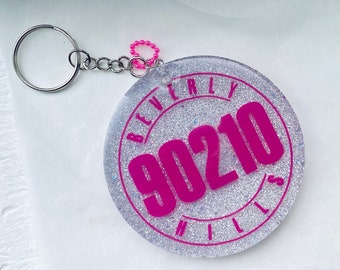 May include: A silver keychain with a pink glitter circle charm that says "Beverly Hills 90210" in pink lettering.