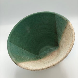 May include: A ceramic bowl with a green and white speckled glaze. The bowl is round and has a wide rim.
