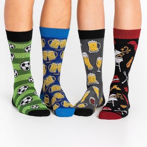 Könnte beinhalten: Gezeigt werden vier Paar Socken. Ein Paar ist grün mit Fußbällen, ein anderes blau mit Bierkrügen, ein drittes grau mit Biergläsern und das letzte schwarz mit Grillmotiven. Jedes Paar hat eine andere Farbe an Zehen und Bündchen.