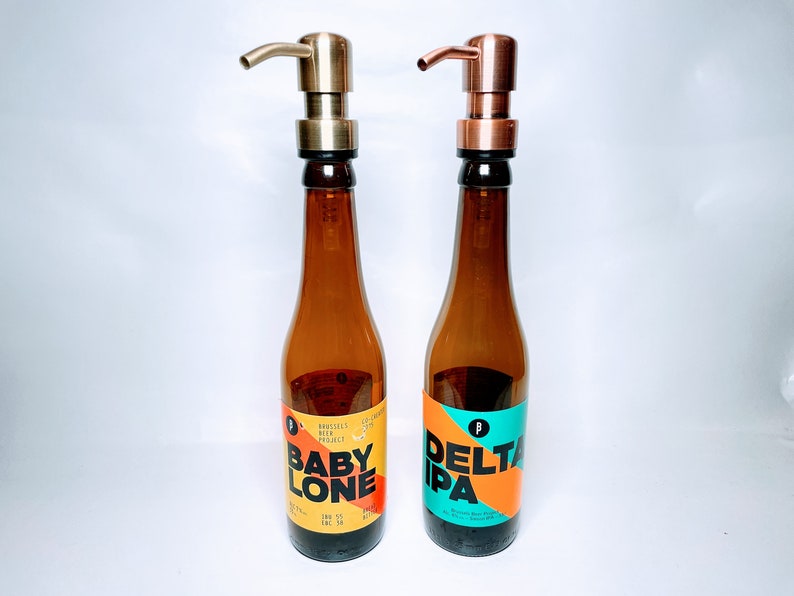 May include: Two brown glass bottles with gold and copper pump tops. The bottles have labels with the text "Baby Lone" and "Delta IPA".