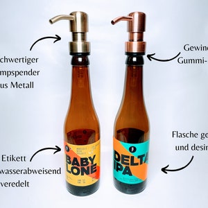 May include: Two glass bottles with labels, one with a yellow and orange label that says "BABY LONE" and the other with a blue and orange label that says "DELTA IPA". Both bottles have gold metal pump dispensers.