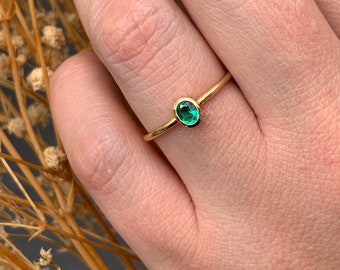 Solitaire ring with oval-cut natural emerald in 18k gold