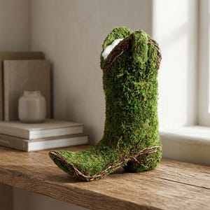 Peut inclure: Une botte de cowboy décorative recouverte de mousse verte vibrante. La botte présente un bout pointu, un talon et est ornée de fines vignes brunes. C'est une pièce de décoration intérieure unique, parfaite pour ajouter une touche de charme rustique.