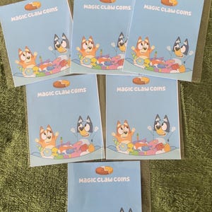 May include: Multiple blue cards in clear plastic, each bearing the text "MAGIC CLAW COINS" and a cartoon dog illustration. The cards are displayed on a green surface.