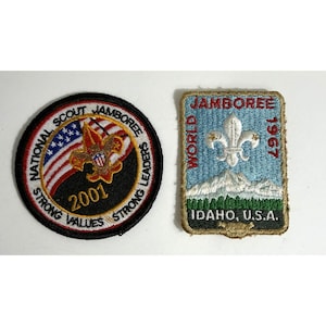 May include: Two embroidered patches. One is round with "NATIONAL SCOUT JAMBOREE 2001 STRONG VALUES STRONG LEADERS" text and a US flag design. The other is rectangular with "JAMBOREE WORLD 1967 IDAHO, U.S.A." text and a fleur-de-lis.