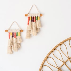 Close up view of two rainbow mini wall hangings hanged above a bed