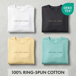 May include: Four folded t-shirts in white, black, yellow, and teal. Each shirt has the text "L'ARTE DEL COTONE" printed on the front. The shirts are made of 100% ring-spun cotton and have the Oeko-Tex label.