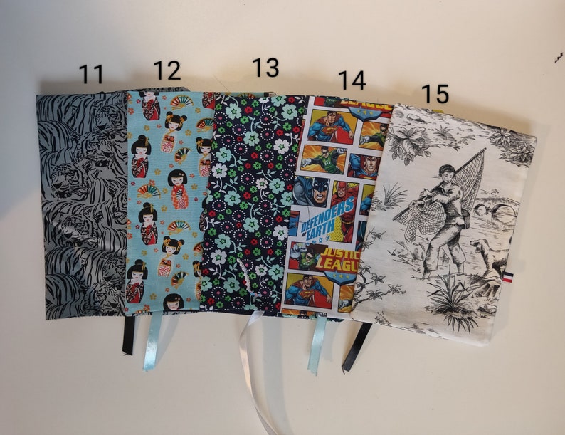 Puede incluir: Diez cubiertas de libros con diferentes dise&ntilde;os. Las cubiertas est&aacute;n hechas de tela y tienen una variedad de patrones, incluyendo tigres, flores y personajes de c&oacute;mics. Las cubiertas est&aacute;n numeradas del 11 al 15.
