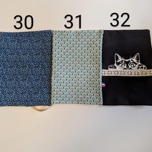 Puede incluir: Tres muestras de tela, cada una con un patr&oacute;n diferente. La primera muestra es una tela azul oscuro con un patr&oacute;n de lunares blancos. La segunda muestra es una tela azul claro y verde con un patr&oacute;n en forma de abanico. La tercera muestra es una tela negra con un gato blanco bordado asom&aacute;ndose por la parte superior.