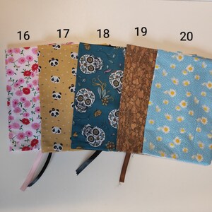 Puede incluir: Cinco cubiertas de libros de tela diferentes con los n&uacute;meros del 16 al 20 impresos en la parte superior. Las cubiertas son de varios patrones, incluyendo flores rosas, amarillo con osos panda, azul verdoso con calaveras de az&uacute;car, corcho marr&oacute;n y azul claro con margaritas blancas.