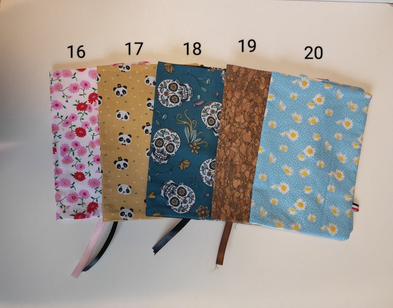 Puede incluir: Cinco cubiertas de libros de tela diferentes con los n&uacute;meros del 16 al 20 impresos en la parte superior. Las cubiertas son de varios patrones, incluyendo flores rosas, amarillo con osos panda, azul verdoso con calaveras de az&uacute;car, corcho marr&oacute;n y azul claro con margaritas blancas.