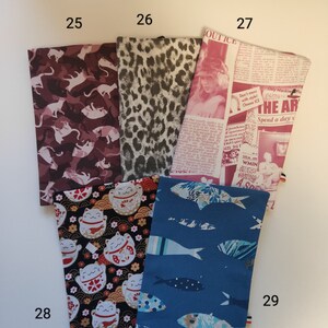 Puede incluir: Cinco muestras de tela diferentes, cada una con un patr&oacute;n &uacute;nico. Las muestras est&aacute;n numeradas del 25 al 29. Los patrones incluyen un estampado de camuflaje rosa y blanco, un estampado de leopardo negro y blanco, un estampado de peri&oacute;dico con el texto "Don't mess with style! Choose ICE", un estampado negro y blanco con un dise&ntilde;o de gato japon&eacute;s de la suerte y un estampado azul con un dise&ntilde;o de pez.