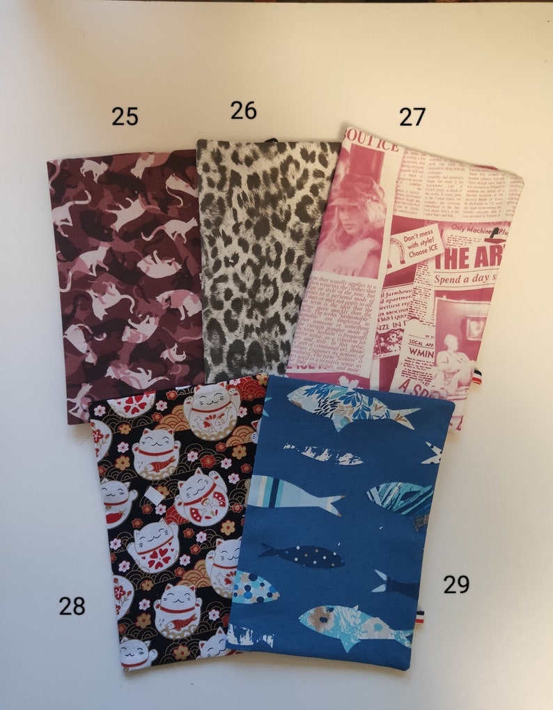 Puede incluir: Cinco muestras de tela diferentes, cada una con un patr&oacute;n &uacute;nico. Las muestras est&aacute;n numeradas del 25 al 29. Los patrones incluyen un estampado de camuflaje rosa y blanco, un estampado de leopardo negro y blanco, un estampado de peri&oacute;dico con el texto "Don't mess with style! Choose ICE", un estampado negro y blanco con un dise&ntilde;o de gato japon&eacute;s de la suerte y un estampado azul con un dise&ntilde;o de pez.