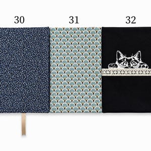 May include: Three rectangular fabric book covers labeled 30, 31, and 32. Cover 30 is dark blue with a small white floral pattern. Cover 31 features a teal and gold fan-shaped pattern. Cover 32 is black with a white cat graphic and lace trim.