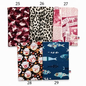 May include: Five rectangular fabric pouches labeled 25 through 29. Number 25 has a maroon cat pattern, 26 features a black and white leopard print, 27 displays a red and white newspaper collage, 28 shows black lucky cats, and 29 has blue fish.