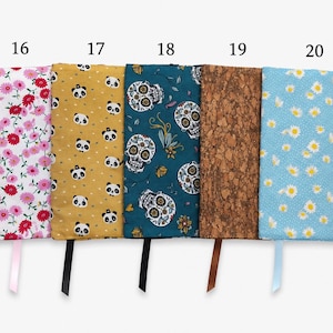 May include: Five rectangular fabric book covers labeled 16 through 20. Patterns include pink flowers on white, pandas on yellow, skulls on teal, a brown cork texture, and white daisies on light blue. Each cover features a matching ribbon bookmark.