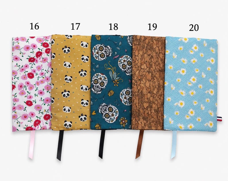 May include: Five rectangular fabric book covers labeled 16 through 20. Patterns include pink flowers on white, pandas on yellow, skulls on teal, a brown cork texture, and white daisies on light blue. Each cover features a matching ribbon bookmark.