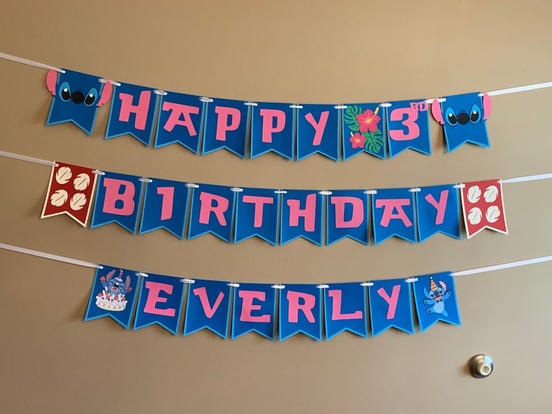Puede incluir: Una pancarta azul y rosa con las palabras "Happy 3rd Birthday Everly" y personajes de Stitch. La pancarta est&aacute; enhebrada en una cuerda blanca.