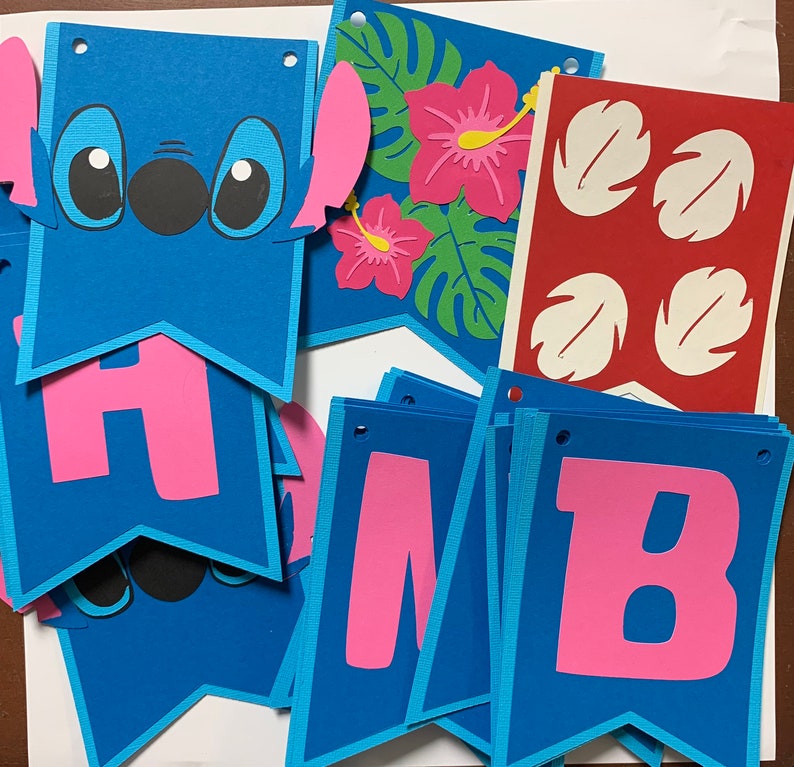 Puede incluir: Una pancarta azul y rosa con las letras "HMB" y un personaje de Stitch. La pancarta est&aacute; decorada con hojas y flores tropicales.