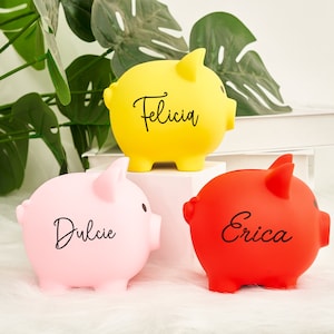 May include: Three piggy banks, one yellow, one pink, and one red, with names written on them: Felicia, Dulcie, and Erica.