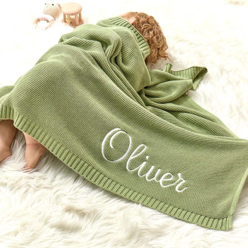 Puede incluir: Una suave manta de punto verde para beb&eacute; con el nombre "Oliver" bordado en blanco.