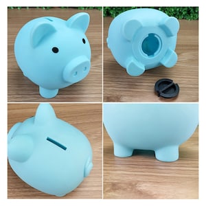 May include: A light blue piggy bank with a slot on the top for coins. The piggy bank has a rounded body and four small feet.