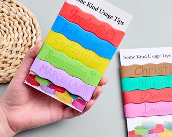 May include: A stack of colorful silicone name tags with the names Frederik, Isabella, Stefany, Samantha, and Marcella. The tags are in red, blue, yellow, green, and purple. The text "Some Kind Usage Tips" is printed on the top of the card.