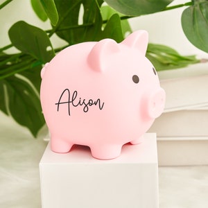 May include: A pink piggy bank with the name "Alison" written on it.