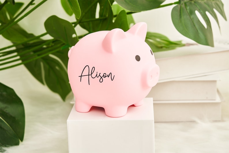 May include: A pink piggy bank with the name "Alison" written on it.
